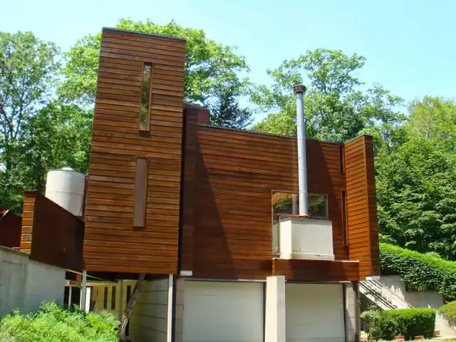 Contemporary stained-cedar house with a tall chimney stack and an attached garage