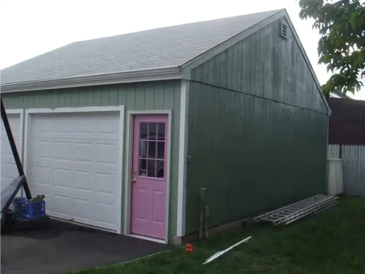 The same garage repainted green, with a pink side door