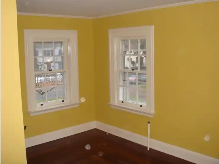 The same bedroom finished in warm yellow with white window trim