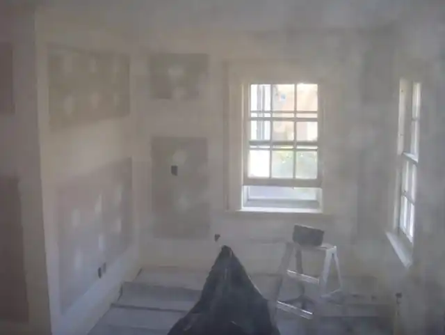 Bare bedroom with patched plaster and drywall seams before painting