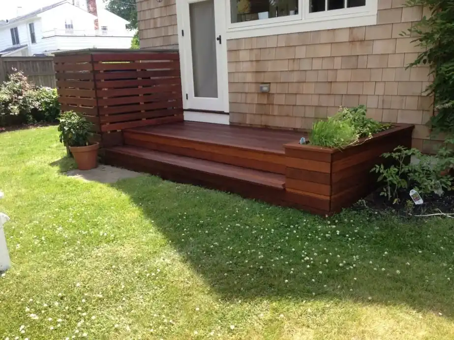 New hardwood deck with a built-in planter bench against a cedar-shingled house