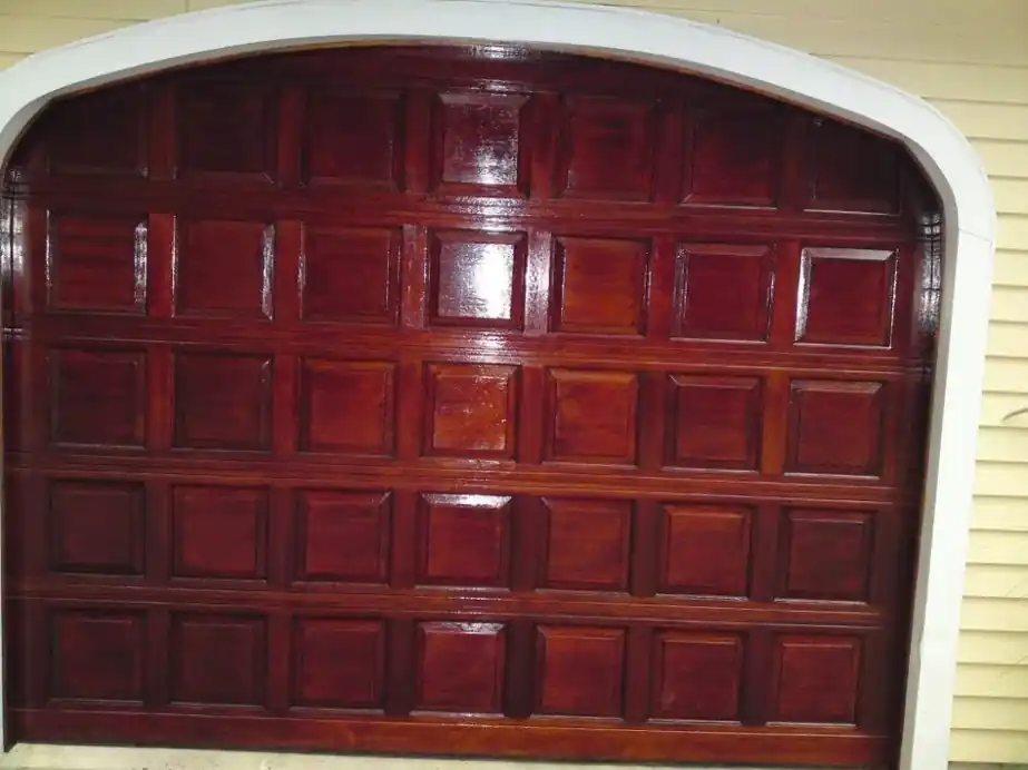 Arched raised-panel garage door finished in a deep mahogany stain
