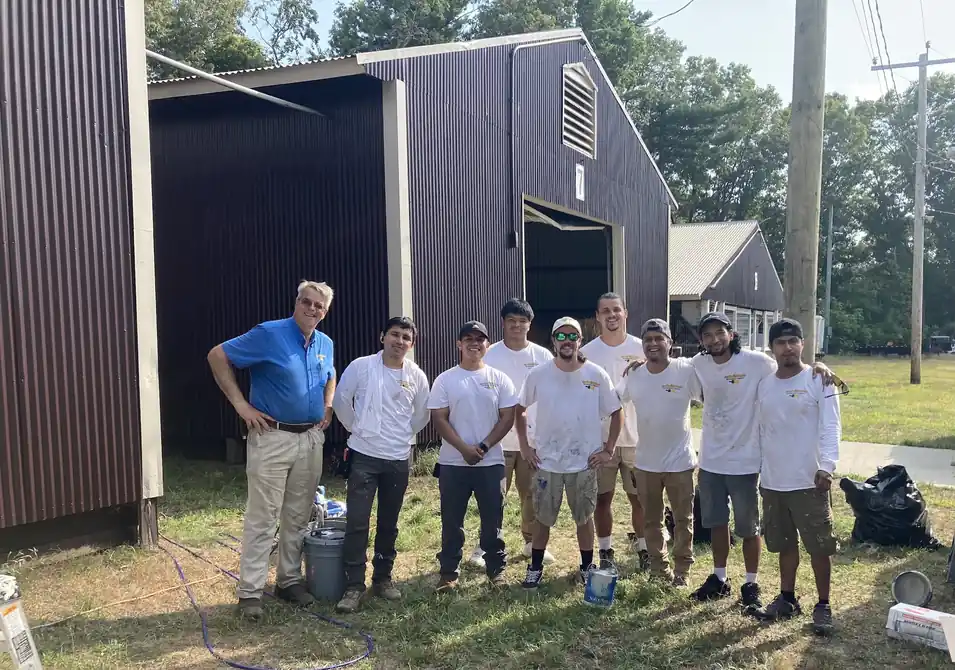 Ray Sola in a blue shirt with the Cloudland crew in white shirts, standing in front of a dark barn